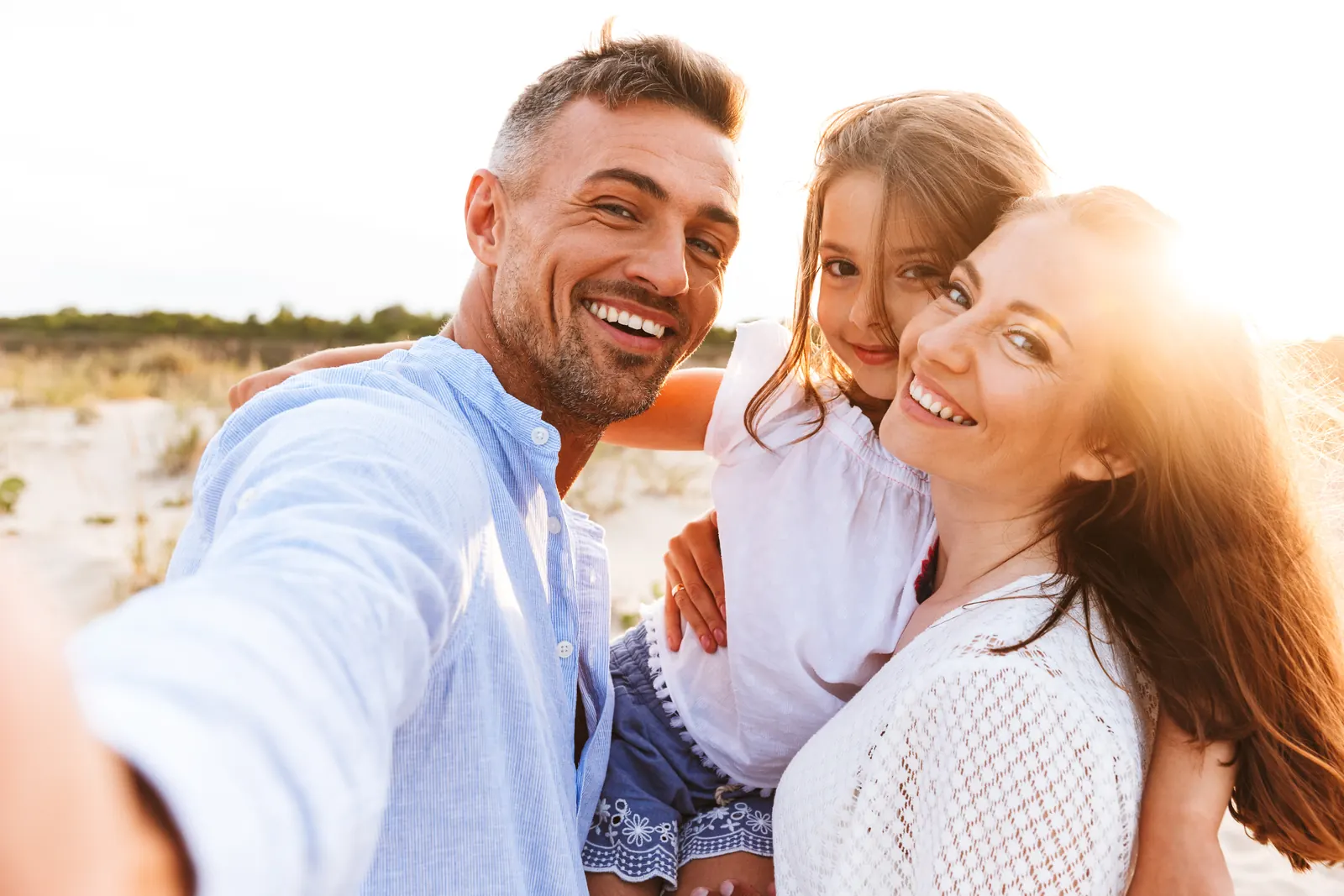 A family of three smiling together outdoors